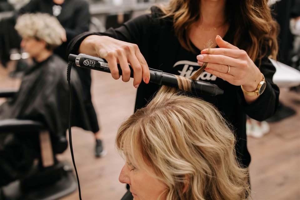 Frisör som lockar håret på sin kund.